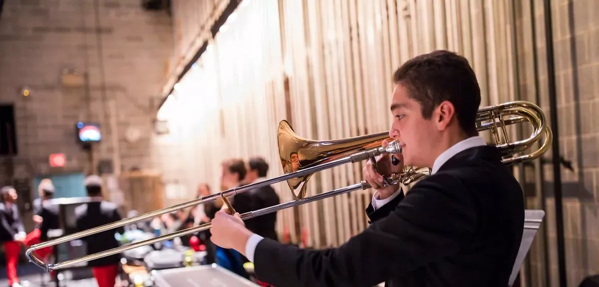 Student in black sweater plays trombone